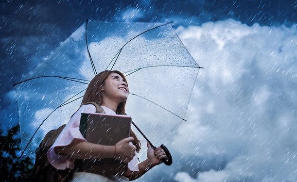 seorang wanita menggunakan payung saat sedang hujan