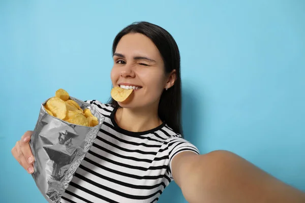 seorang wanita memakan keripik kentang