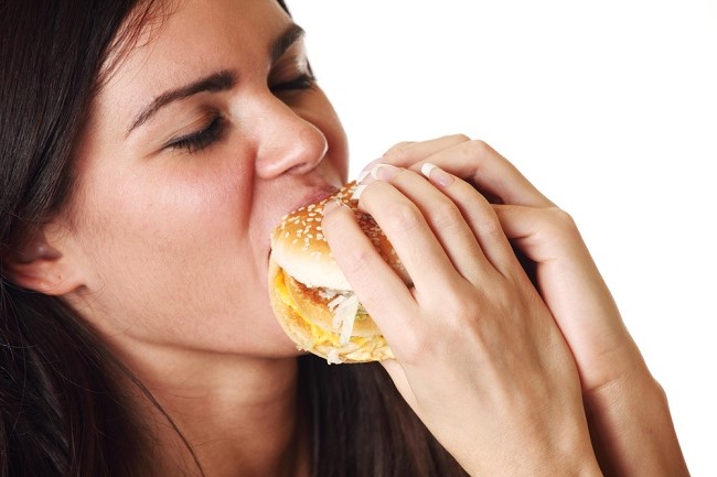 seorang wanita memakan burger